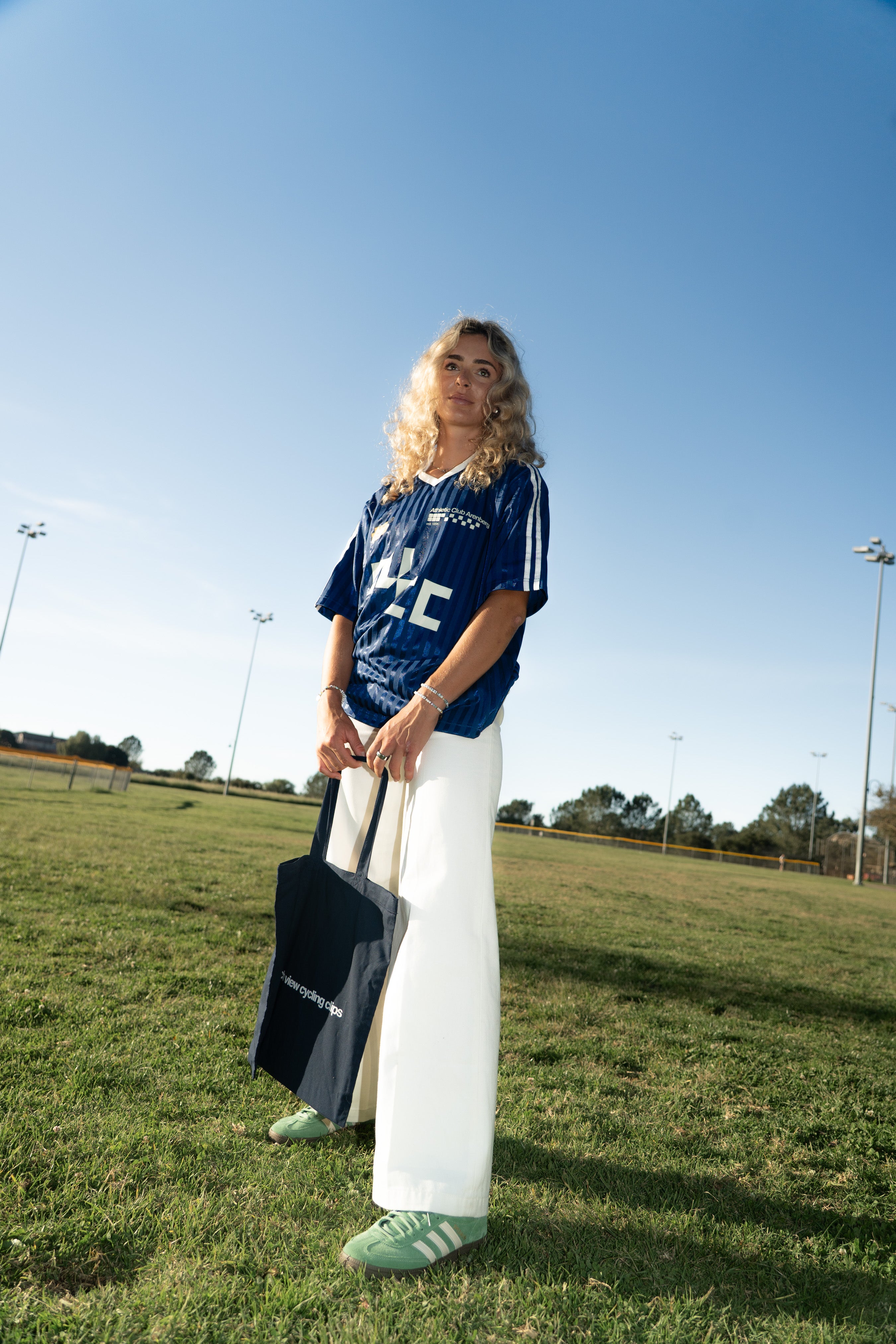 Person wearing a blue couch view jersey and white pants standing on a grassy field with a clear blue sky.