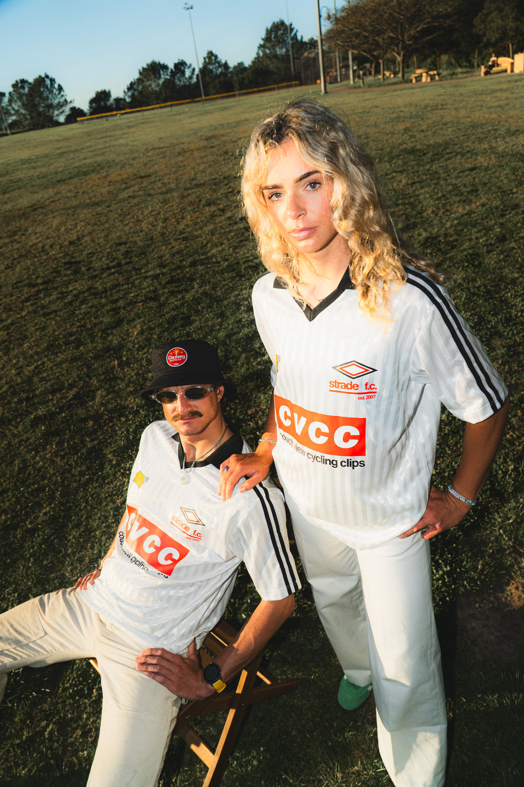 Two people in white sports uniforms with couch view branding on a grassy field.