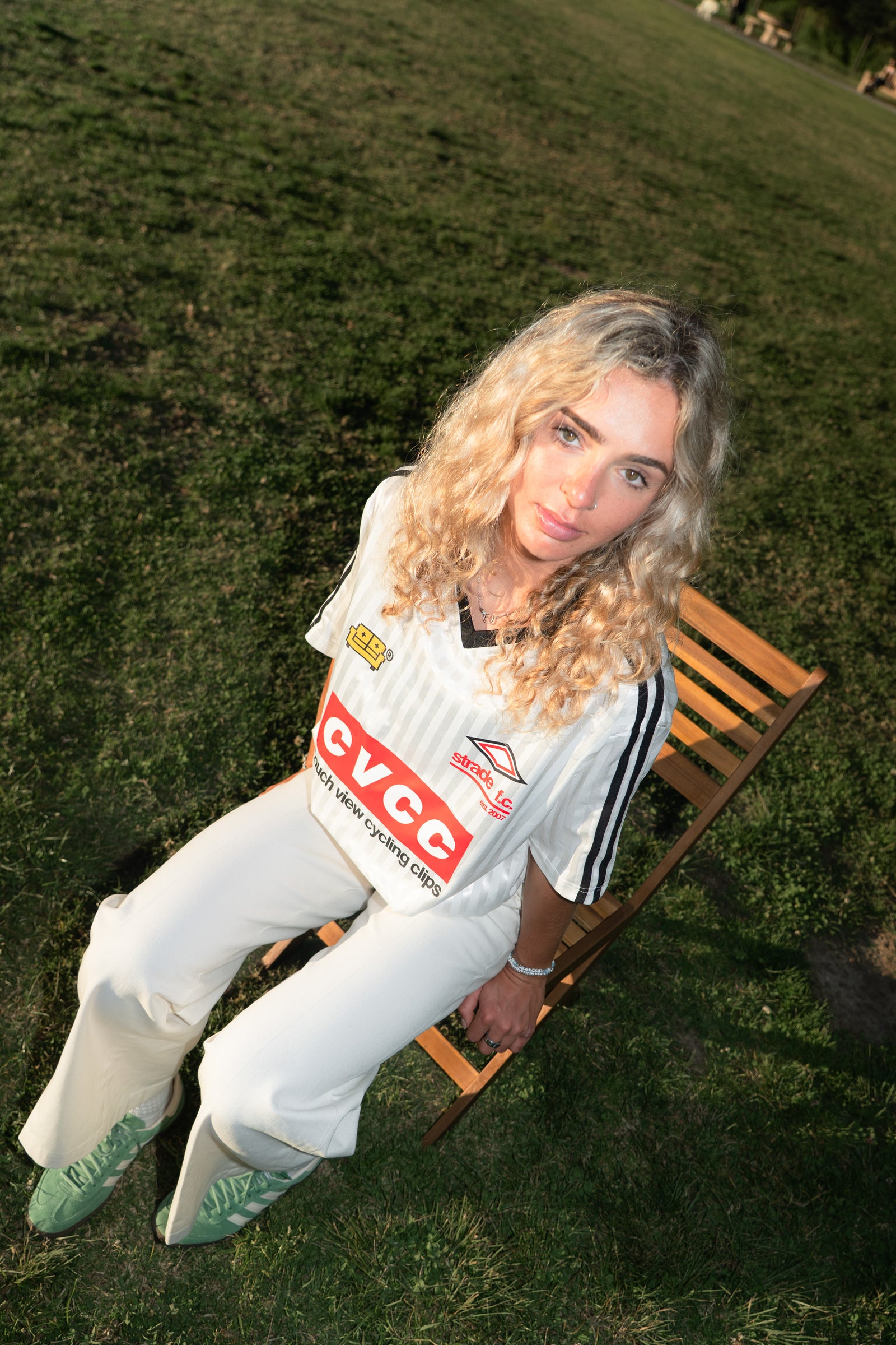 Person sitting on a wooden bench outdoors wearing a sports jersey with visible couch view branding.