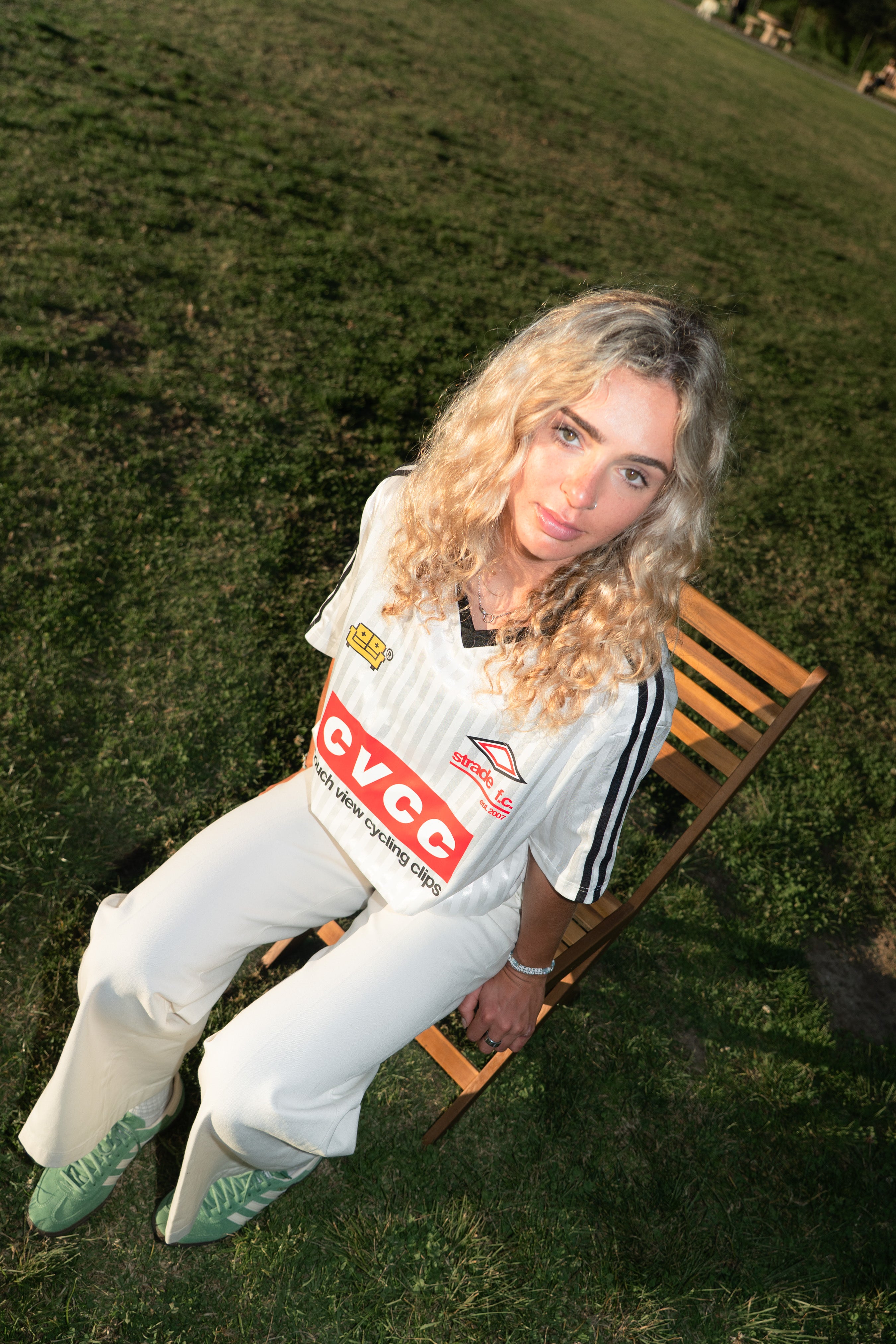 Person sitting on a wooden bench outdoors wearing a sports jersey with visible couch view branding.