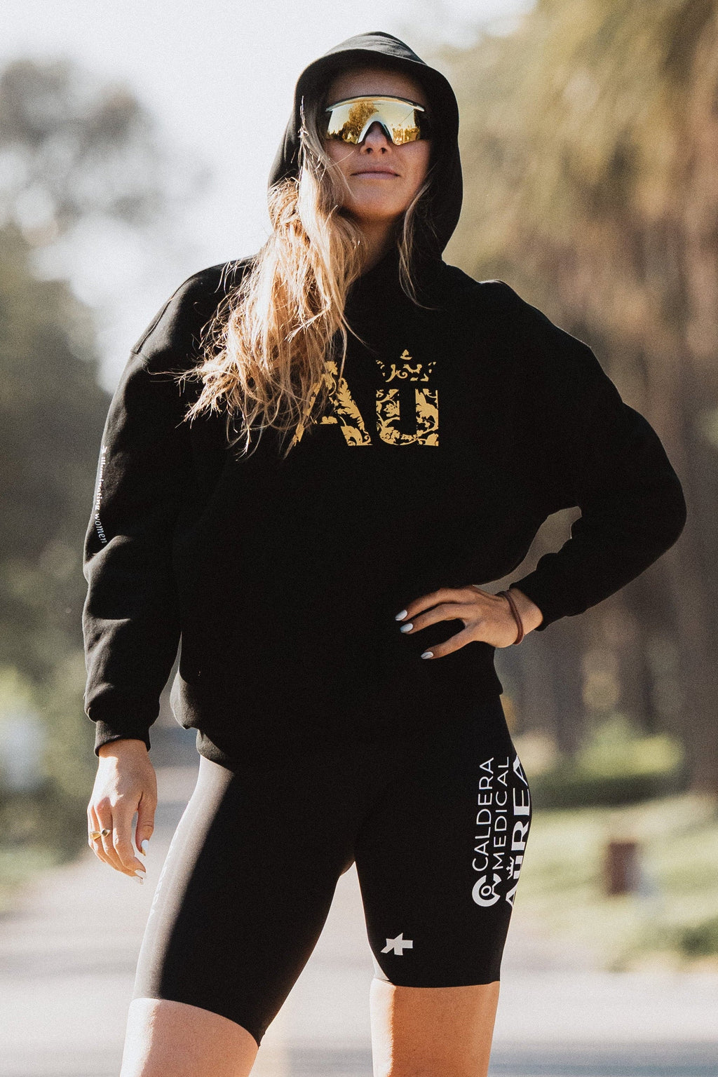 Person wearing a black hoodie and shorts with visible branding on a road.